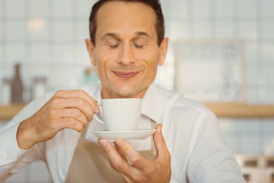 快乐的积极的男人品尝咖啡