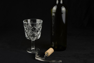 黑布桌盖上装有酒瓶和软木开瓶器的酒杯