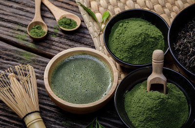 日本有机抹茶绿茶粉在碗里，用铁丝打蛋器和木制背景的绿茶叶，来自大自然的有机健康产品，具有传统的风格