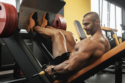 Bodybuilder doing a seated leg press exercise in a