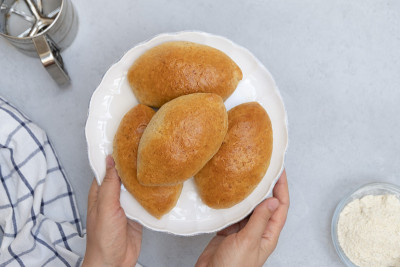 女人手里拿着一个白色的盘子，里面放着塞满馅料的包子(Pirozhki)，这是一种俄罗斯和乌克兰烤或炸