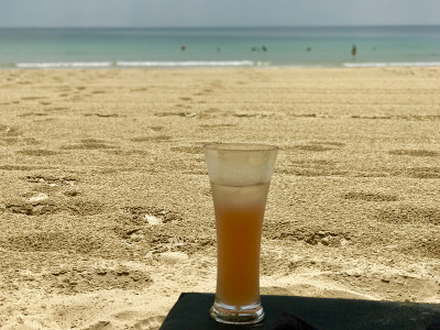 在潮湿的沙滩上，在躺椅上喝着水果鸡尾酒
