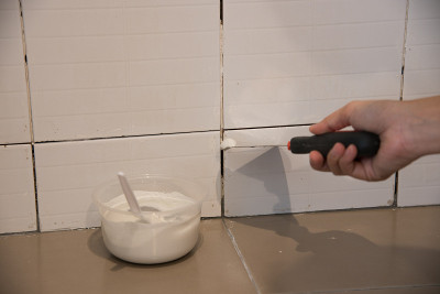 DIY。用镘刀修补墙壁上的瓷砖，清除空隙缝中残留的胶水，安装新的胶水或白色硅胶，铺砖和饰面技术。