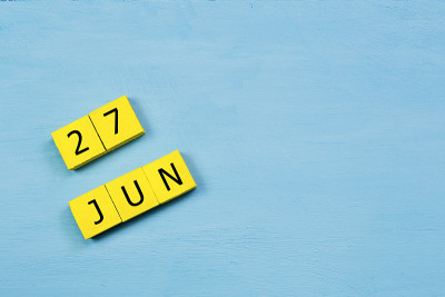 6月27日，黄色立方体日历，蓝色木质表面，有拷贝空间