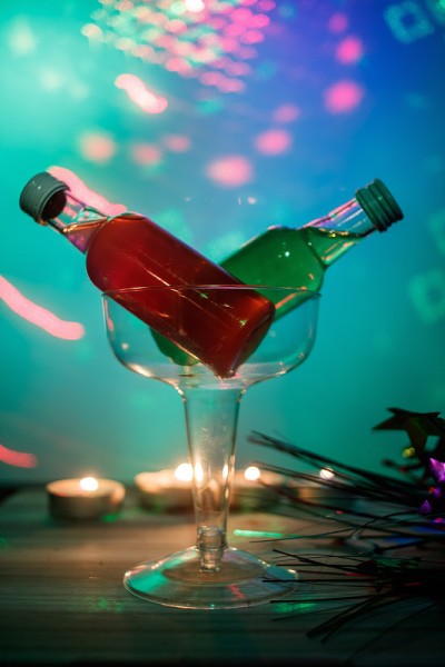 色彩鲜艳的酒瓶子在鸡尾酒杯与蓝色和绿色的海景色背景在派对或俱乐部安排