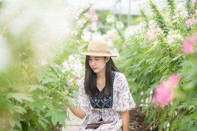 身穿黑色马鞭草背心、披着彩色披肩、戴着草帽的美丽女子，在紫色的马鞭草花海中摆姿势，一头乌黑长发的迷人