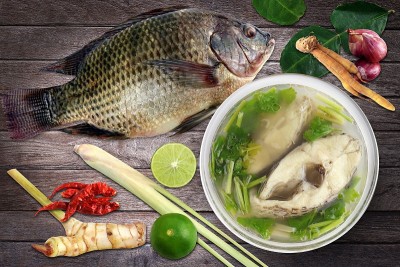 罗非鱼清汤和煮罗非鱼清汤和配料咖喱木背景(汤yampla泰语)，片片鱼汤辣杯，泰式食物罗非鱼煮酸辣汤