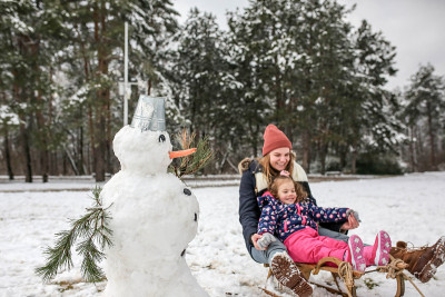 母亲和女儿在一个寒冷的冬天拉雪橇和堆雪人
