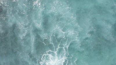 在黄金时刻飞过海洋。巨大的波浪在海洋中激起泡沫和水花。夏威夷瓦胡岛上的太平洋海水的蓝绿色。