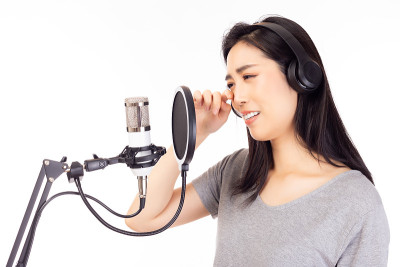 女歌手在录音棚里唱着悲伤的歌曲或心碎的歌曲，用麦克风，流行滤镜来录制音乐。女歌手在录音棚里哭着，然后