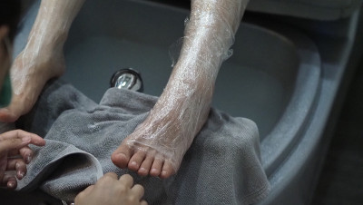 脚Spa。在水疗店的肥皂水机里，女人光脚按摩。女人的脚进入脚浴在热水手持式。在水疗沙龙用脚油按摩。放