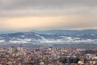 皮罗市上空五彩缤纷的天空和远处残雪连绵的群山