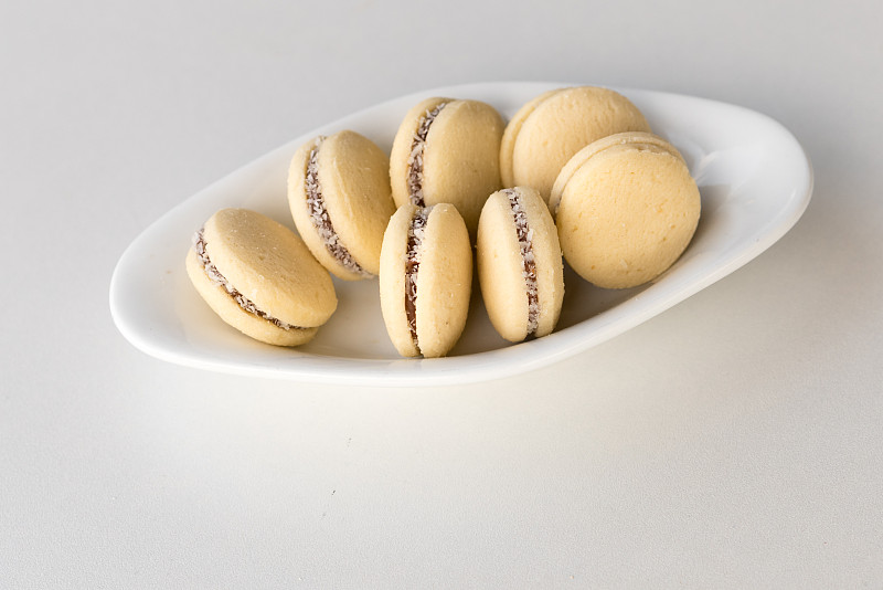 俯视图Alfajores，焦糖酥饼和椰子卷。白色盘子上的阿根廷马卡龙