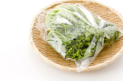 新鲜的绿叶生菜装在竹制滤锅上，白色背景，