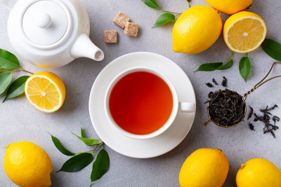 Tea cup and pot with lemon. Grey background. Close