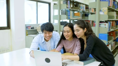 三名大学生在笔记本电脑上互相帮助做项目