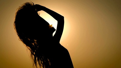 一个无名的女人在夕阳的背景下颤抖着头发