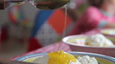 农家干酪，酸奶油和蜂蜜放在盘子里。用农家干酪旋转盘子。蜂蜜滴在农家干酪上
