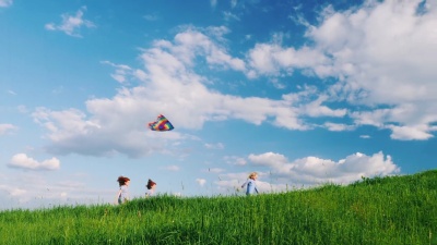 有趣而无忧无虑的孩子们在绿色的草地上奔跑，玩着风筝。快乐童年