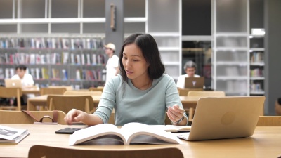 亚洲女学生使用智能手机进行图书馆教育，读书和做笔记
