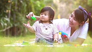 亚洲妈妈和宝宝在户外玩得很开心。一起在绿色夏季公园。妈妈和孩子。快乐的家庭微笑。春天公园里美丽的家庭享受大自然。