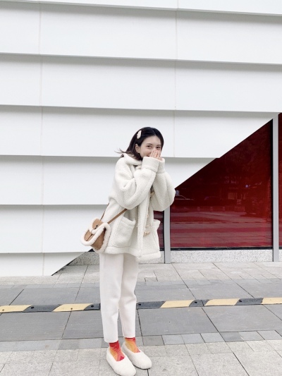 服饰系列实景模特穿着白色毛绒外套和白色长裤的室外摆拍