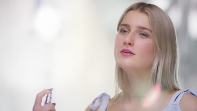 美丽年轻女子颈部喷洒香水的近照