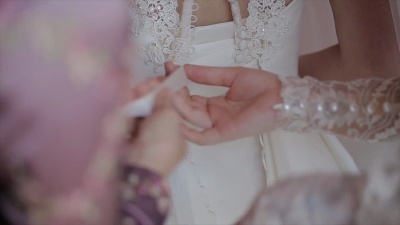 男人在新娘的婚纱上系上胸衣