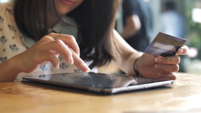 女性在数字平板电脑上使用信用卡购物