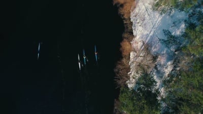  航空镜头俯视河面上的三条独木舟，春天在桥下靠近海岸的地方