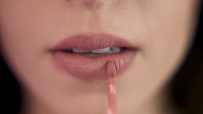 特写迷人的女孩涂着腮红的嘴唇。