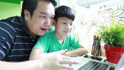 快乐的亚洲父子在笔记本电脑上浏览互联网。