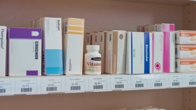 一位女士伸手到药店架子上的维生素瓶并检查标签