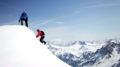 登山者互相帮助到达白雪覆盖的山峰