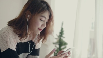 亚洲女人坐在沙发上听音乐