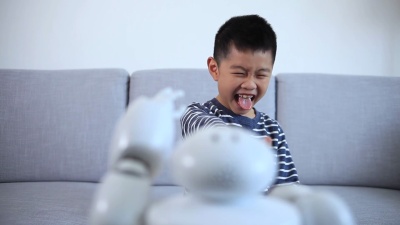 聪明的男孩做个鬼脸并赞扬机器人