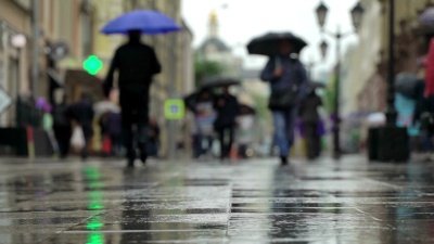 城市街道雨天的背景。实时。人们在雨中打着伞上下班。模糊的波克。自然背景