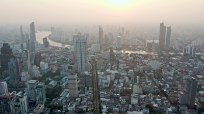 俯瞰泰国曼谷城市，主要商业区有湄南河和高层办公楼，背景是日落。