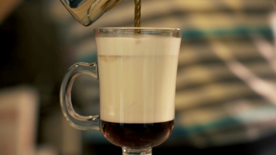 咖啡师在自助餐厅用加牛奶的玻璃杯倒咖啡准备拿铁