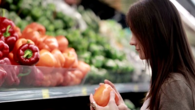 年轻女子在商店货架上挑选红辣椒