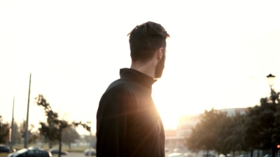 令人难以置信的男人回头看的电影镜头。后视慢动作。令人惊叹的太阳耀眼的光芒。反思与思考