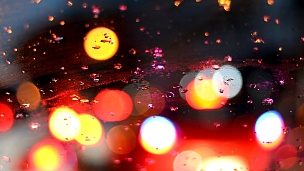 在雨天天气的城市街道上驾驶汽车，在交通堵塞的城市道路上，雨滴落在车辆的挡风玻璃上。