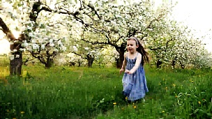 小女孩跑过一个开花的花园