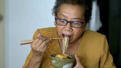 老年妇女在吃早餐时使用平板电脑。