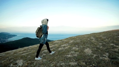 女徒步旅行者背着背包在山上行走