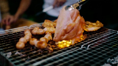 厨师用钳子在烤架上翻肉