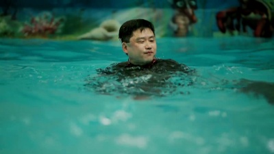 亚洲男子与海豚游泳