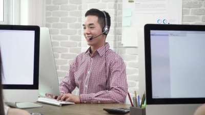 微笑的亚洲男子电话销售客户服务代理与客户交谈