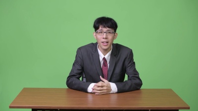 年轻的亚洲商人，作为新闻播音员，在背后讲话和展示一些东西