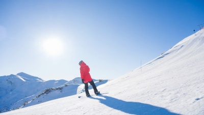 在一个阳光明媚的日子，在白雪覆盖的山上单板滑雪